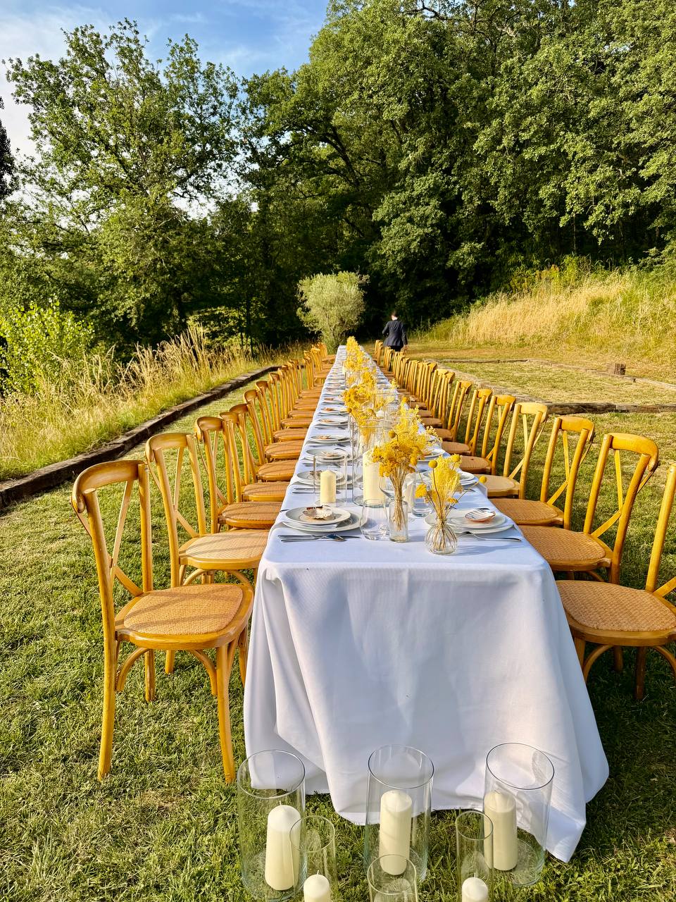Mit Kerzen gedeckte Hochzeitstafel entlang einer Wiesenallee im Wald von Les Cazettes